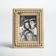 a wooden frame with beaded trim around the edges holds an image of three people