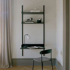 a chair and desk in front of a wall with bookshelf on it, next to a window