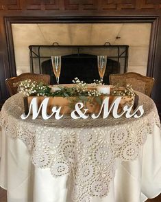 a table with two wine glasses on it and mr and mrs sign at the top