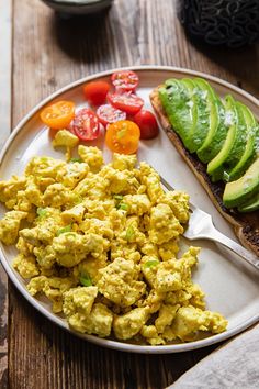 a plate with eggs, avocado and tomatoes on it next to toasted bread