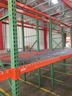 an empty warehouse with lots of metal shelves and orange bars in the middle of it