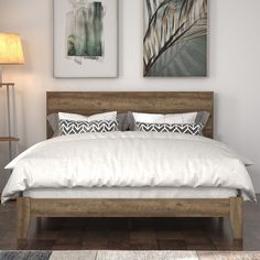 a bed with white sheets and pillows in a room next to two pictures on the wall