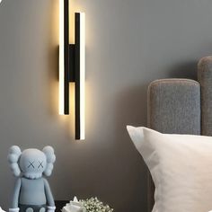 a teddy bear sitting on a table next to a lamp that is on the wall