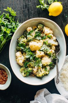 a bowl filled with broccoli and cauliflower next to some lemons