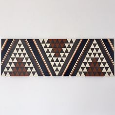 a wall hanging on the side of a white wall with a brown and black pattern