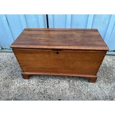 an old wooden chest sitting on top of a cement floor next to a blue wall