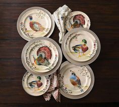 four plates with turkeys painted on them are sitting on a wooden table next to napkins