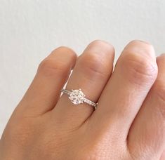 a woman's hand with a diamond ring on top of her finger, showing the side view