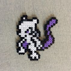 the pixel art is made out of black, white and purple beads on a gray surface