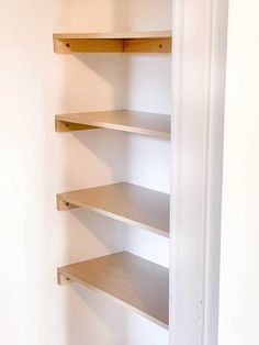 an empty shelf in the corner of a room with white walls and no one on it