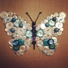 a butterfly made out of buttons sitting on top of a brown cloth covered floor next to a wall