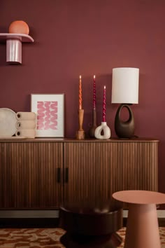 a living room with purple walls and wooden furniture on top of the dresser next to a lamp