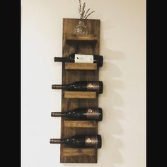 a wooden wine rack with six bottles on it and a vase in the middle is mounted to the wall