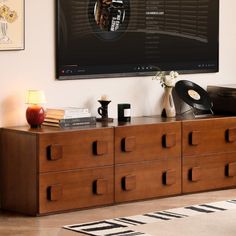 a record player sitting on top of a wooden dresser next to a wall mounted tv