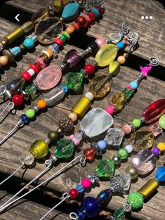 many different colored beads and pins on a wooden table