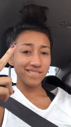 a woman sitting in the back seat of a car with her hand up to her head