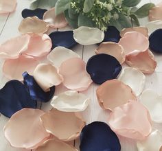 some pink and blue petals on a white table next to a vase with flowers in it