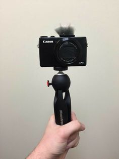 a person is holding up a camera to take a photo with it's tripod