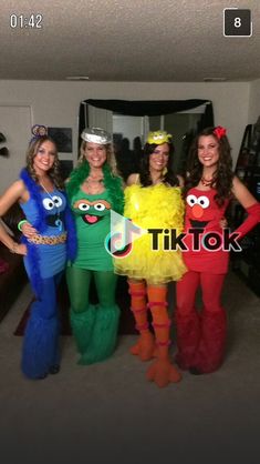 four women dressed in costumes posing for a photo with sesame characters on their faces and arms