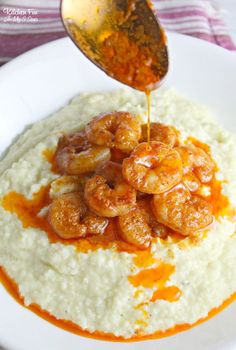 shrimp and grits being drizzled with gravy on a white plate