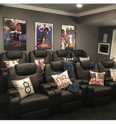 a couple of couches with pillows on them in front of some pictures and posters