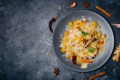 a white plate topped with rice next to spices and an orange peel on the side