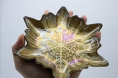 a hand holding a decorative glass bowl in it's palm