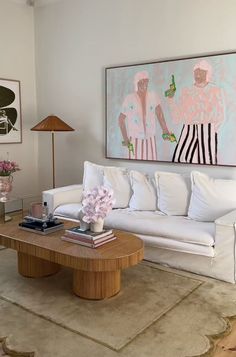 a living room filled with furniture and a painting on the wall above it's coffee table