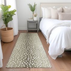 a bed with white sheets and pillows on top of it next to a potted plant