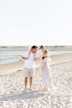 a man and woman standing on top of a sandy beach