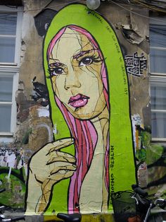 a painting on the side of a building shows a woman with pink hair