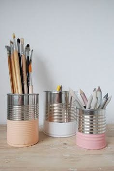 two tin cans with pencils in them sitting on a table