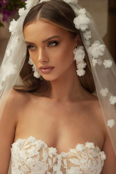 a woman wearing a wedding veil with flowers in her hair