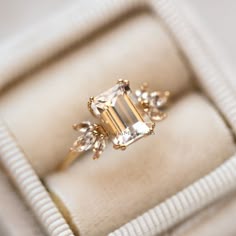 an engagement ring in a box with some diamonds on it's sides and the center stone surrounded by smaller stones