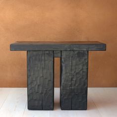 a wooden bench sitting on top of a hard wood floor next to a brown wall