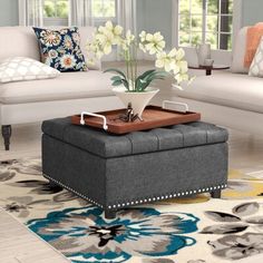 a living room filled with furniture and flowers on top of a coffee table in front of a window