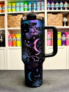 a purple and black travel mug sitting on top of a counter next to shelves filled with bottles