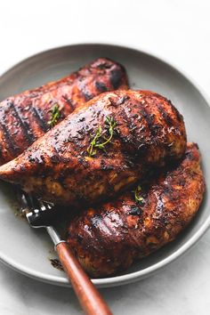 two grilled chicken on a plate with a fork