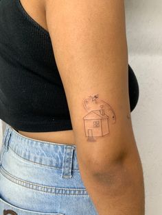 a woman's arm with a small tattoo of a house and a bird on it