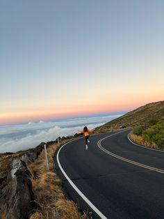 a person riding a skateboard down the side of a road next to a hill