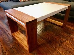 a white table sitting on top of a wooden floor next to a gray couch in a living room