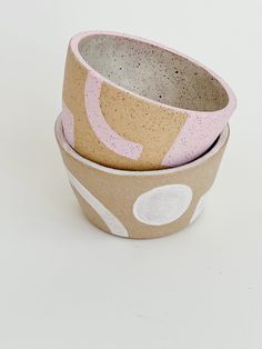 three bowls are stacked on top of each other, one has pink and white designs