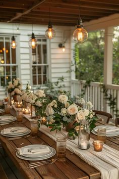 an outdoor dining table set with white flowers and candles