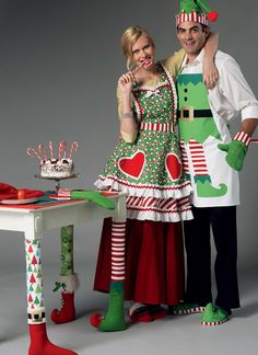 a man and woman dressed up in christmas themed costumes standing next to a table with candy canes