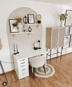 a white desk sitting on top of a hard wood floor next to a wall mounted shelf