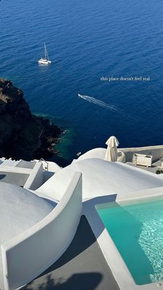 an outdoor swimming pool next to the ocean with a boat in the water behind it