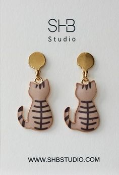 These adorable cat-shaped dangle earrings are the perfect accessory for any cat lover. Featuring a charming blue and grey tabby cat design with gold-tone accents, these earrings bring a playful yet elegant touch to your look. Made from lightweight, Stainless steel and alloy charm materials, they are comfortable to wear all day long, whether you're dressing up for a special occasion or adding a fun statement piece to your everyday style. Grey Tabby Cat, Cat And Moon, Grey Tabby, Moon Lovers, Animal Earrings, Jewellery Gift, Tabby Cat, Cat Design, Everyday Style