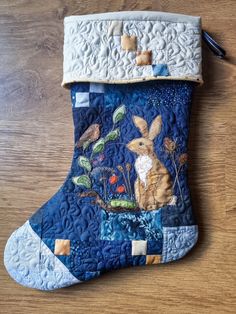 a blue christmas stocking with an image of a rabbit in the woods on it