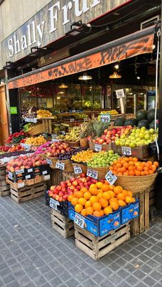 an outdoor fruit stand with lots of fruits on display in front of it's storefront