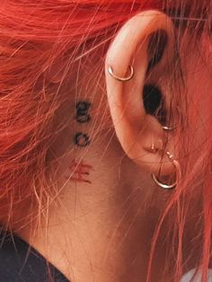 a woman with red hair and piercings on her ear